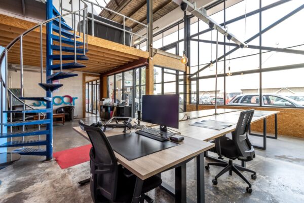 Modern kantoor aan de Eendrachtlaan met industriële inrichting, glazen wanden en een blauwe wenteltrap.