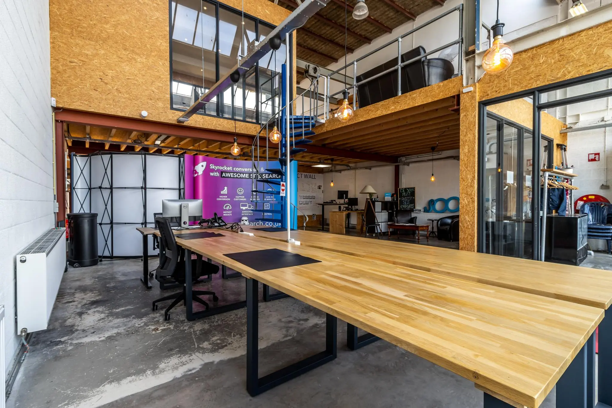 Modern industrieel kantoorinterieur aan de Eendrachtlaan met houten bureaus, open werkplekken en een mezzanine.