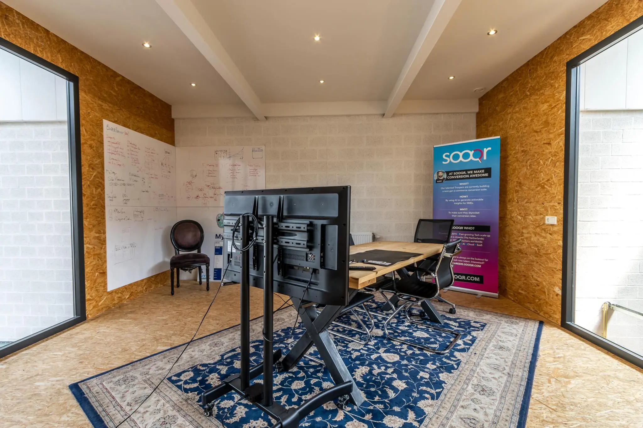 Moderne vergaderruimte aan de Eendrachtlaan met een groot scherm, whiteboards en een Sooqr-promotiebanner.