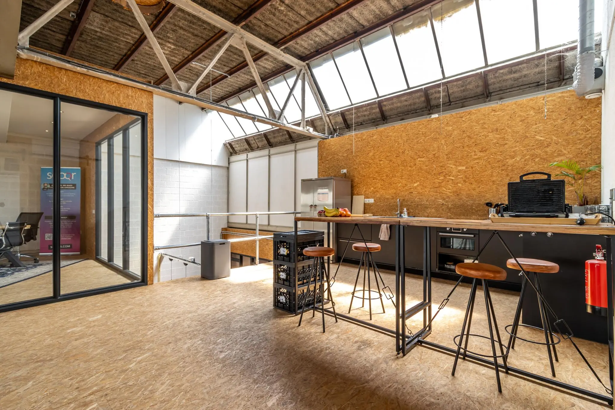 Industriële kantoorkeuken aan de Eendrachtlaan met hoge plafonds, houten accenten en een moderne bar met krukken.