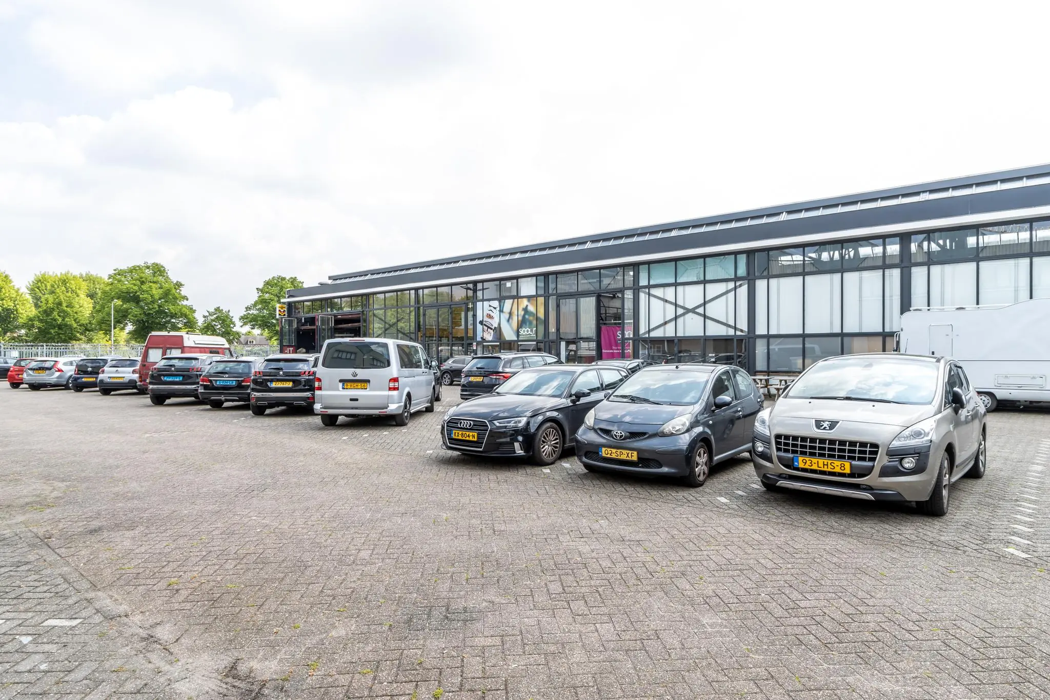Parkeerterrein met geparkeerde auto's voor een modern kantoorgebouw aan de Eendrachtlaan.