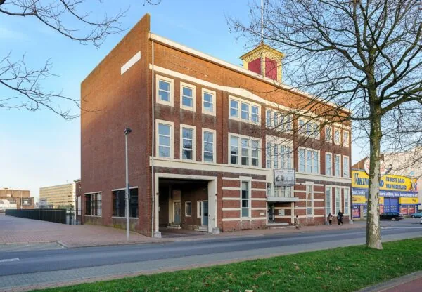 Voormalig schoolgebouw aan de Stadionweg in Rotterdam met een karakteristieke rode bakstenen gevel en te huur-bord aan de voorzijde.