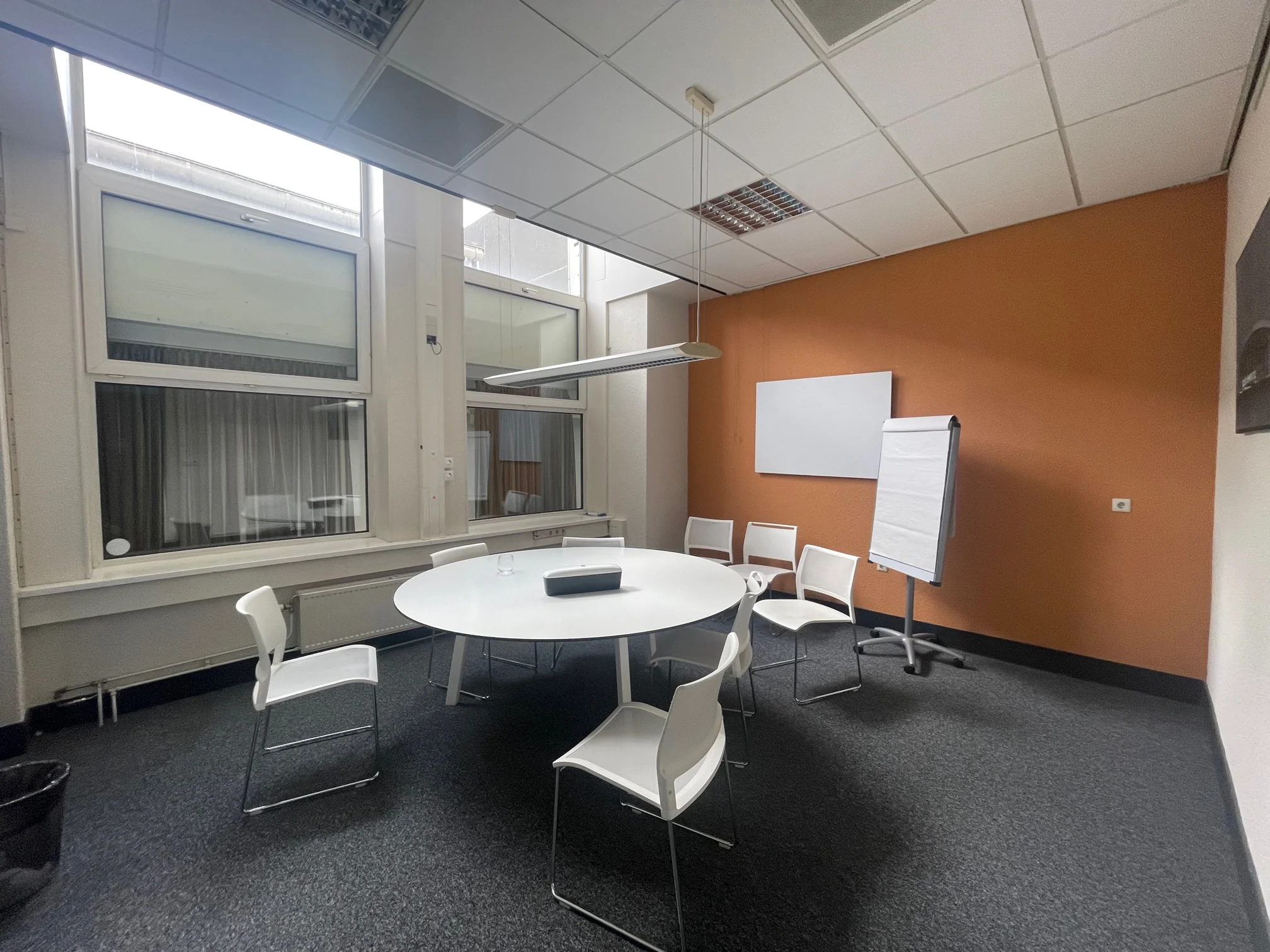Moderne vergaderruimte aan de Stadionweg met ronde tafel, zes stoelen, een flipover en een witbord.