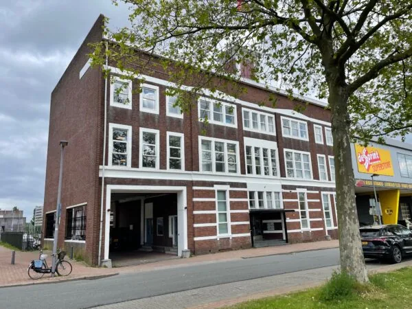 Bakstenen kantoorpand aan de Stadionweg met witte raamkozijnen en naastgelegen drukkerij De Sprint Superstore.