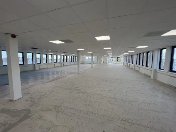 Leeg kantoorpand aan de Vlierbaan met grote ramen en systeemplafond.