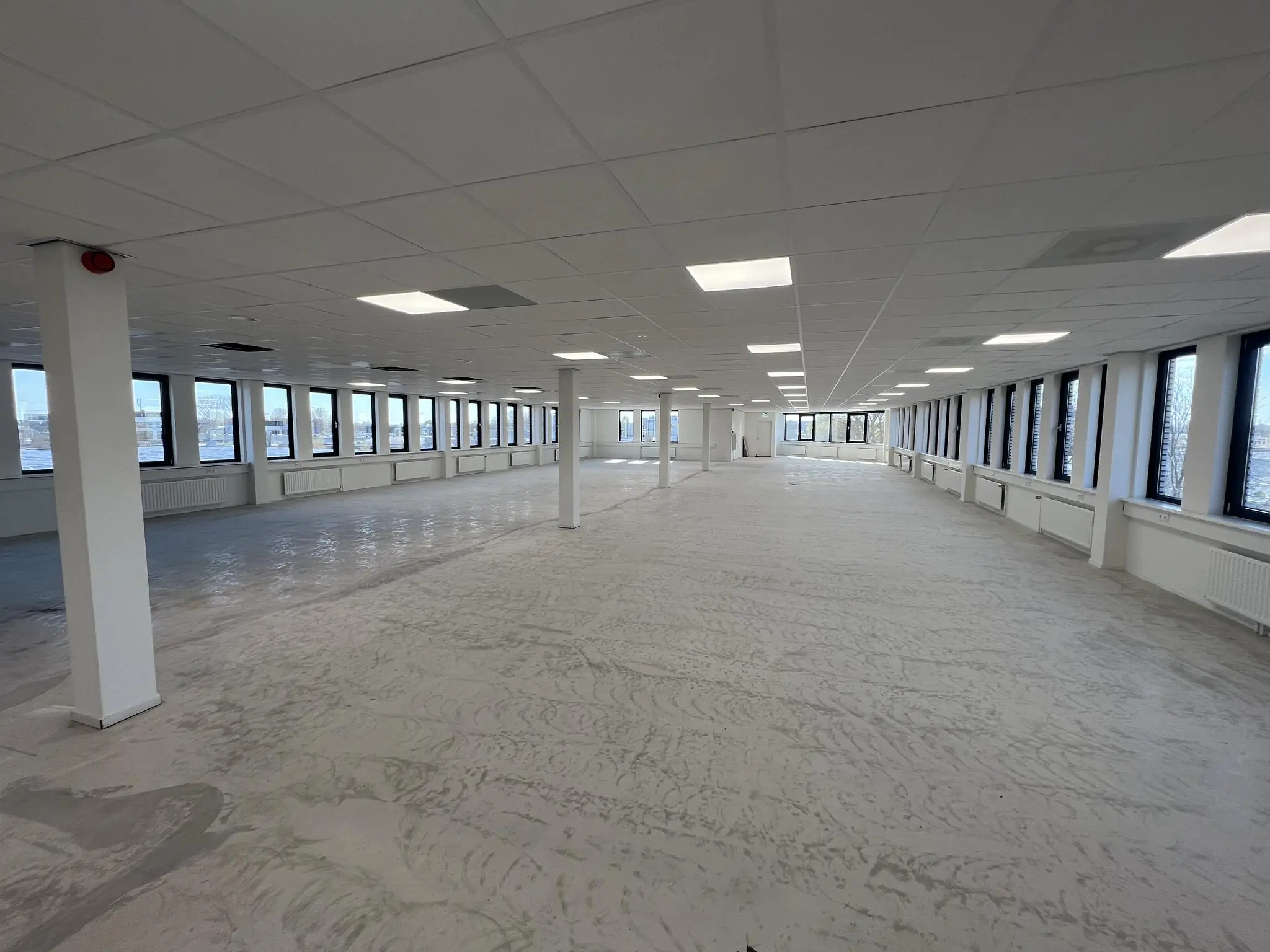 Leeg kantoorpand aan de Vlierbaan met grote ramen en systeemplafond.
