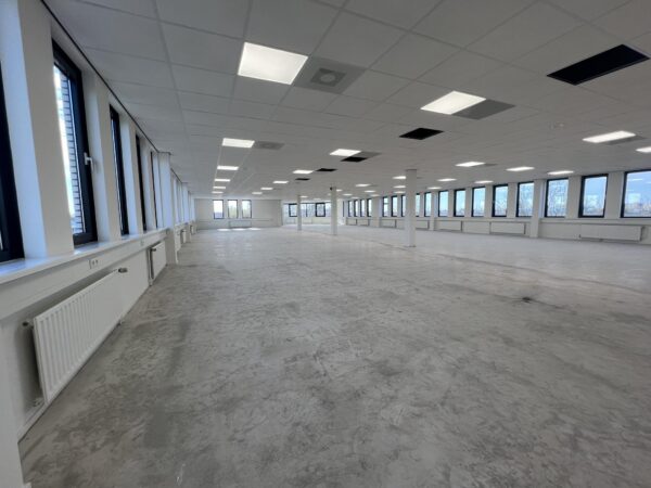 Leeg, ruim en licht kantoor- of bedrijfsruimte aan de Vlierbaan met grote ramen en systeemplafond.