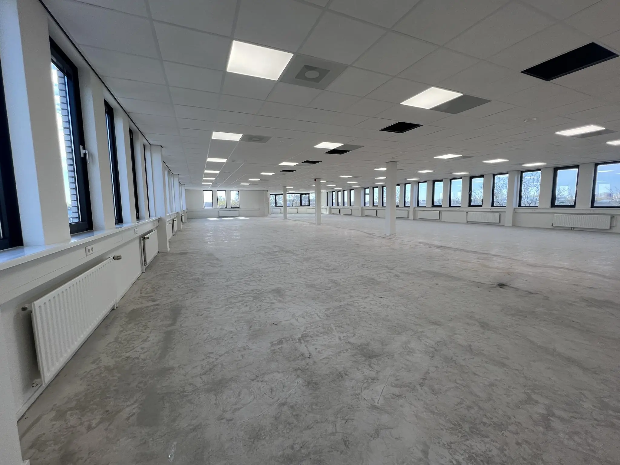 Leeg, ruim en licht kantoor- of bedrijfsruimte aan de Vlierbaan met grote ramen en systeemplafond.