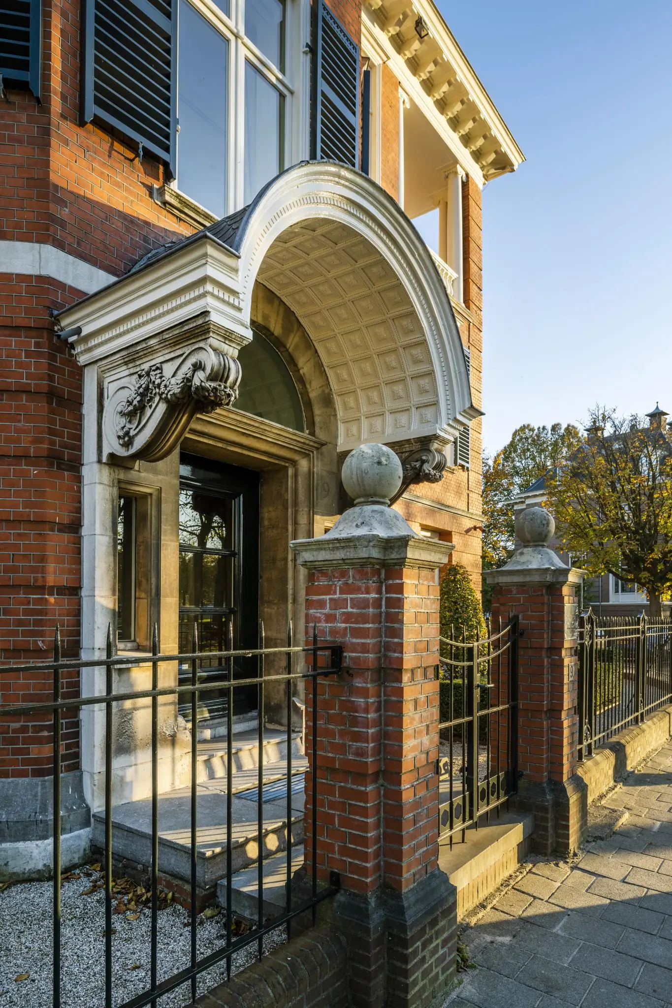 Rijke entree van een statig herenhuis aan het Museumplein met sierlijke boog, natuurstenen details en smeedijzeren hekwerk.