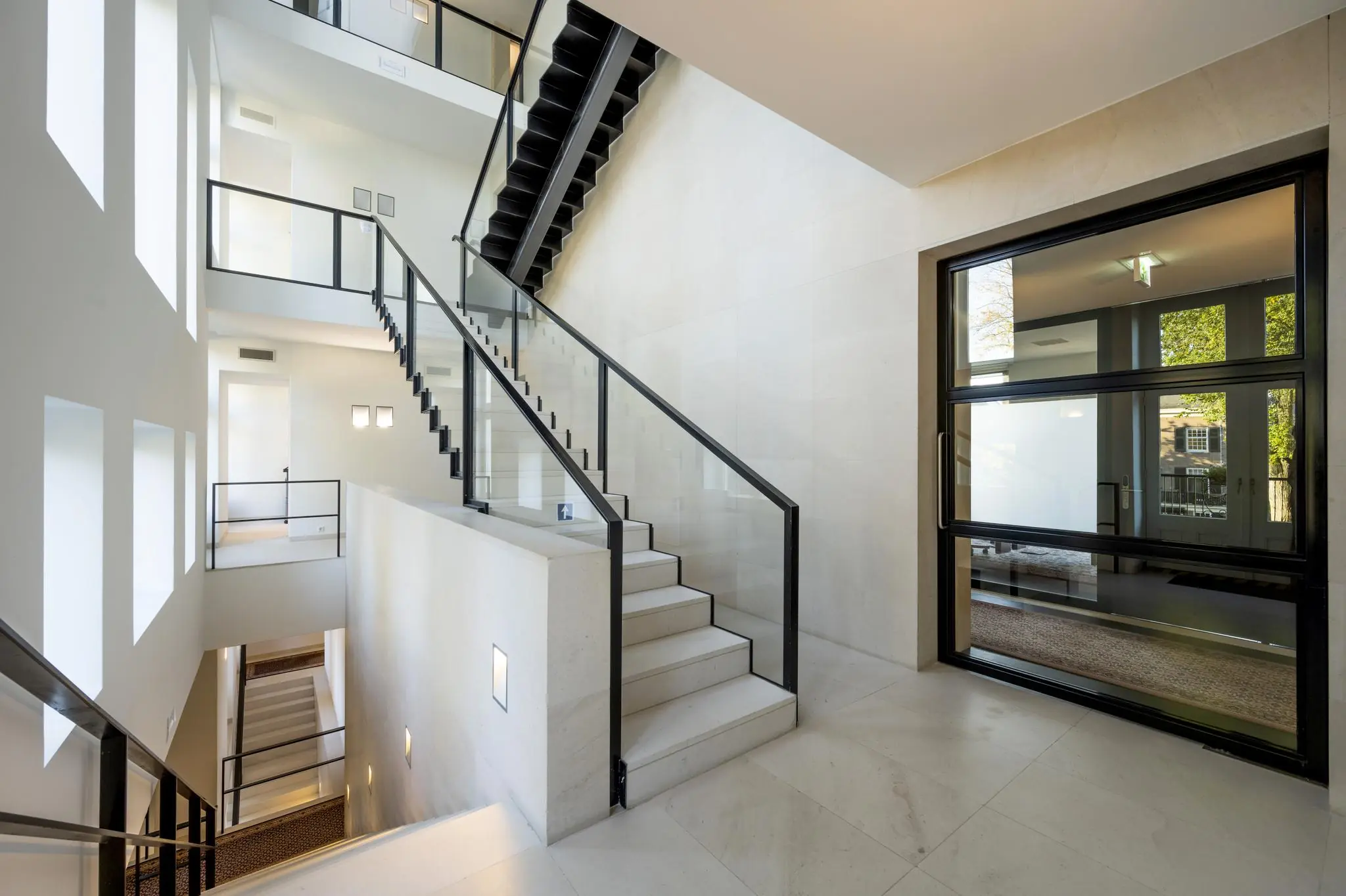 Modern trappenhuis met glazen balustrades en grote ramen in een gebouw aan het Museumplein.