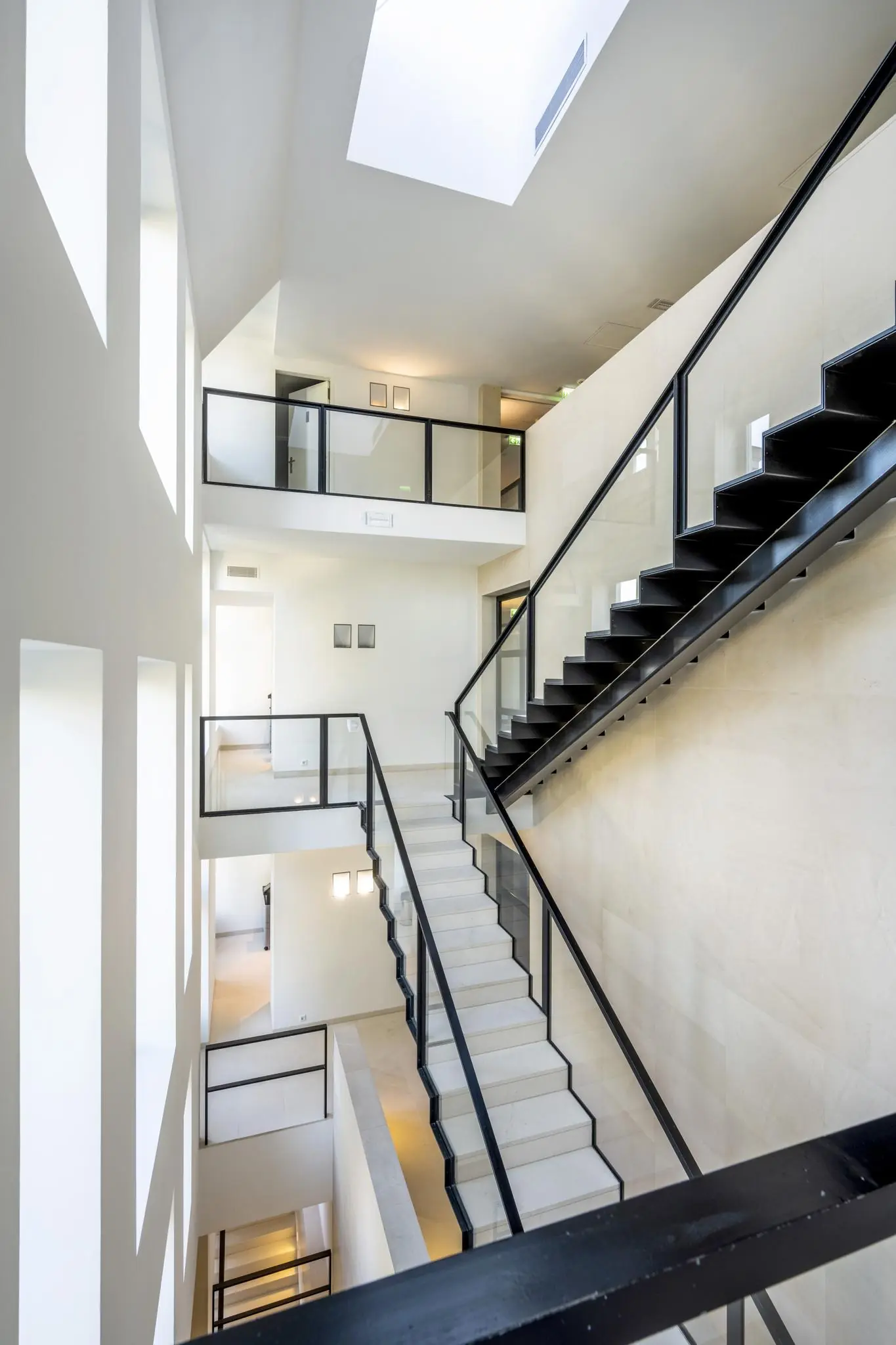 Moderne, licht overgoten trappenhuis met zwarte leuningen in een gebouw aan het Museumplein.