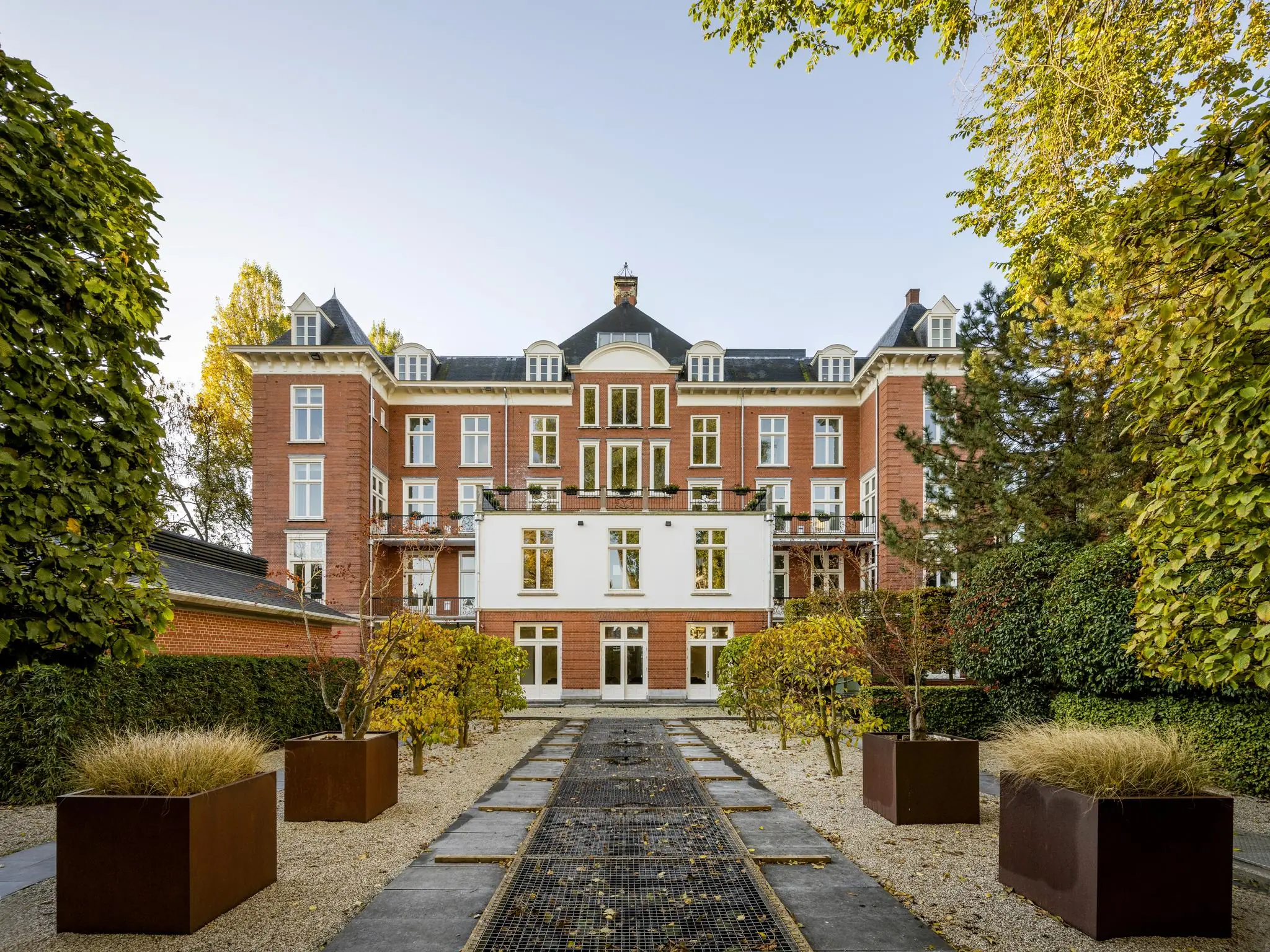 Buitenaanzicht van een statig, historisch herenhuis aan het Museumplein met symmetrisch aangelegde tuin.