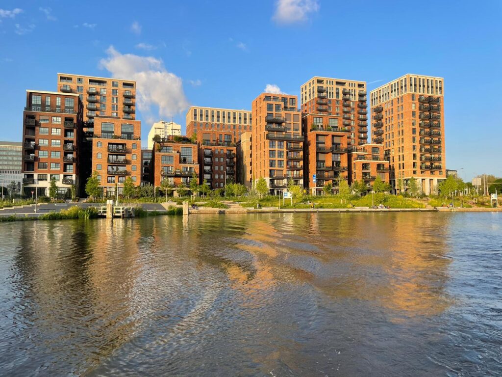 Moderne bakstenen appartementencomplexen aan het water onder een heldere blauwe lucht.