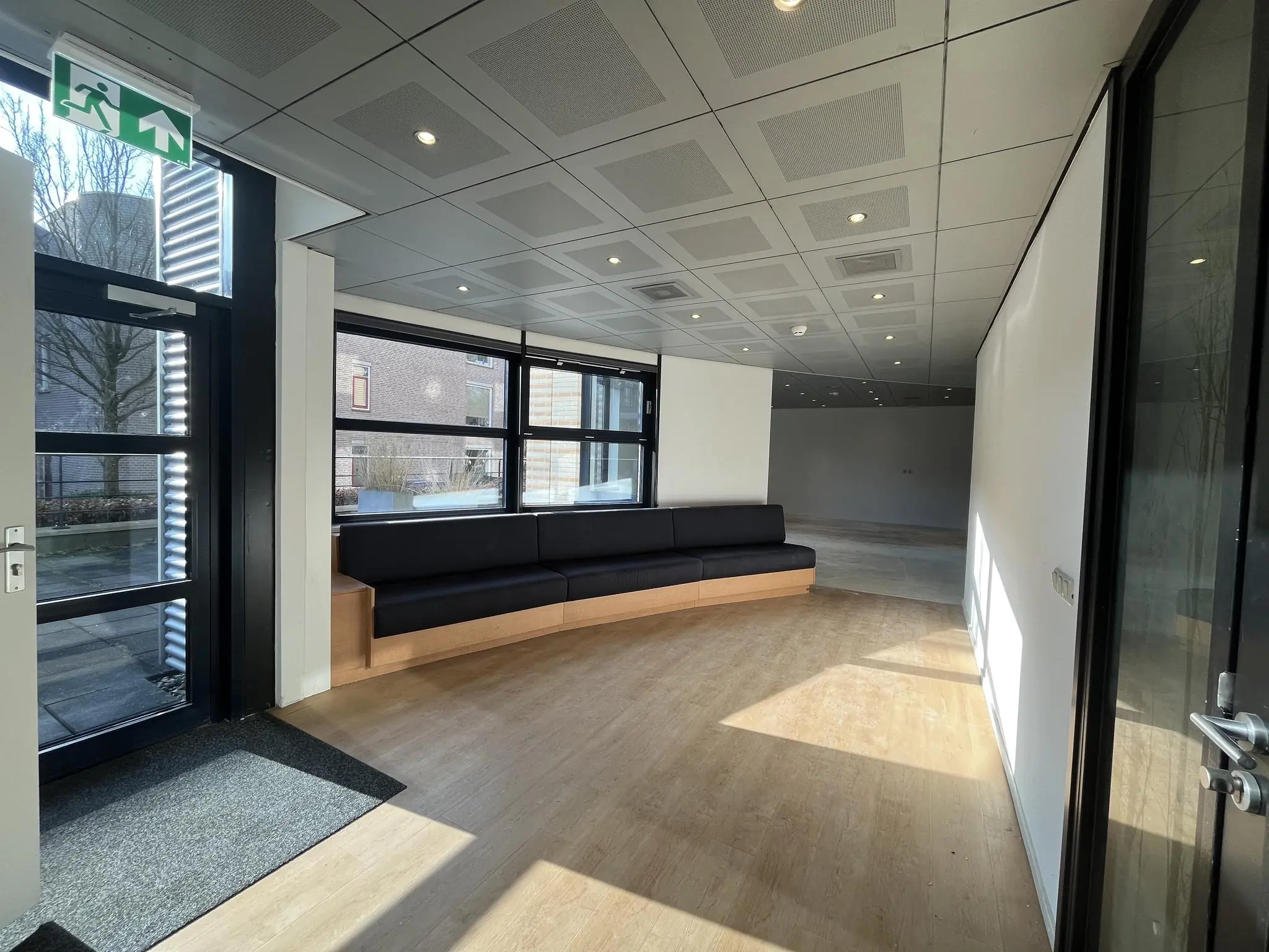 Moderne wachtruimte met zwarte hoekbank en grote ramen aan de Amersfoortseweg.