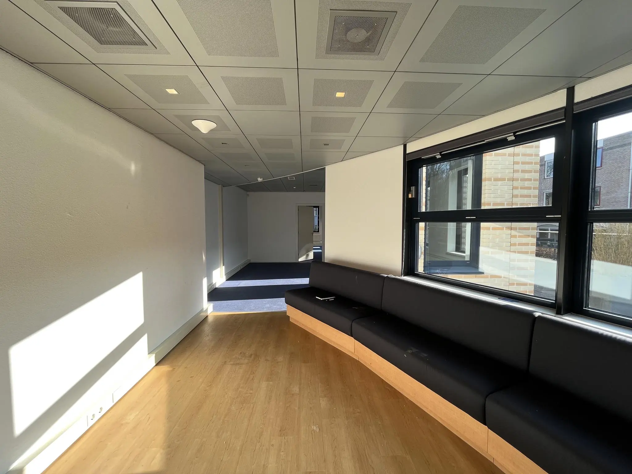 Wachtkamer met zwarte zithoek en grote ramen aan de Amersfoortseweg.