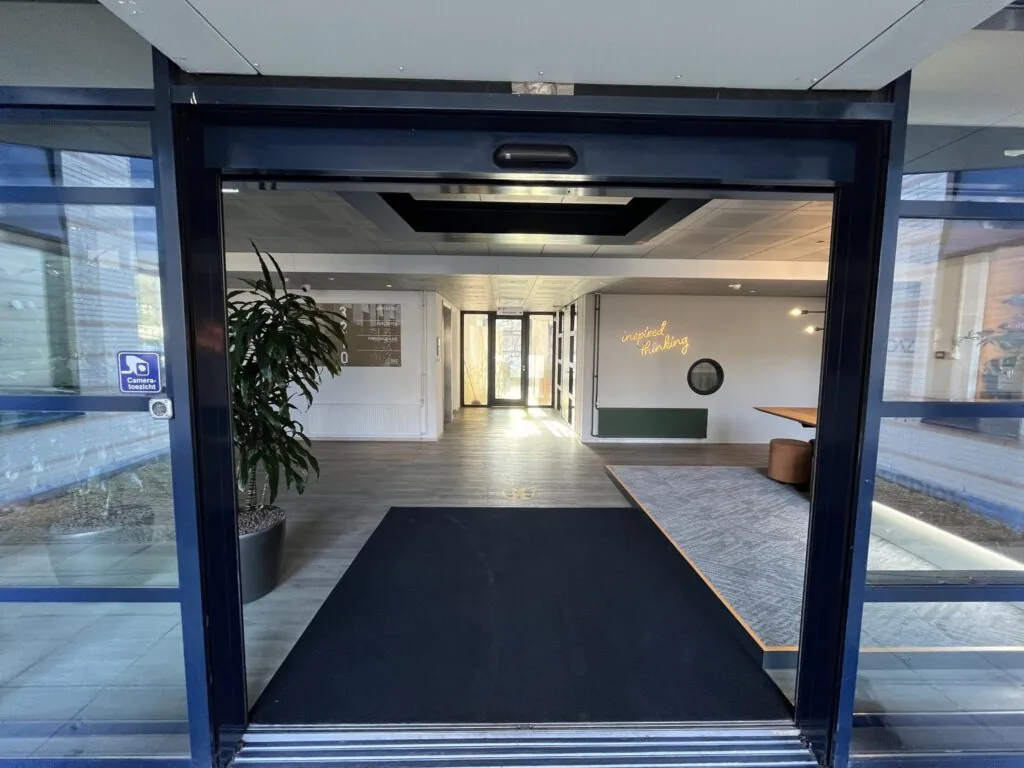 Entree van een modern kantoorgebouw aan de Amersfoortseweg met zicht op een hal en de tekst “inspired thinking” aan de muur.