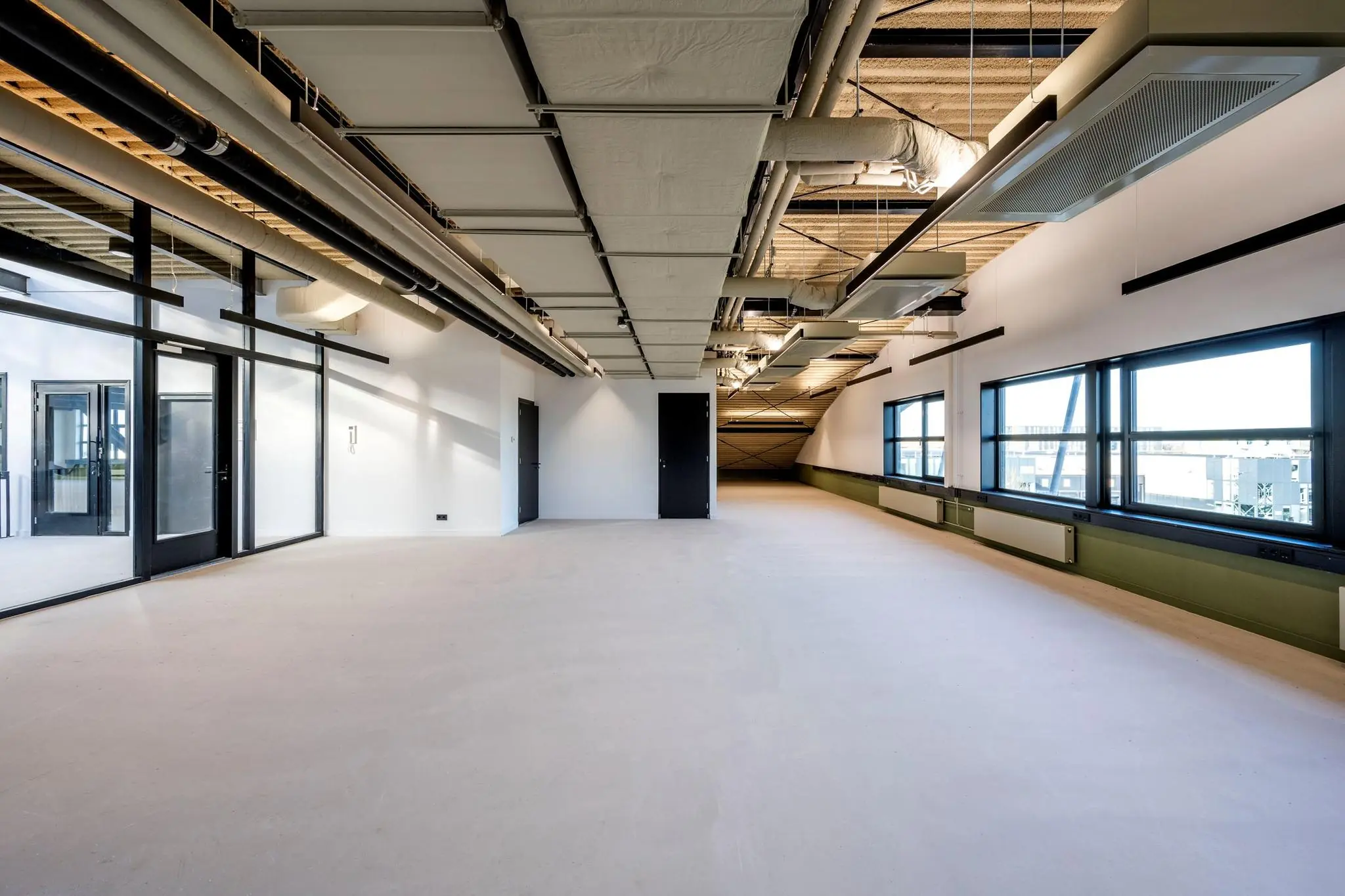 Moderne, lege kantoorruimte aan de Singaporestraat met zichtbare plafondinstallaties en grote ramen.