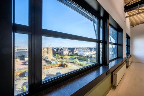 Uitzicht vanuit een modern kantoorpand op de Singaporestraat met woningen, parkeerplaatsen en een waterpartij.