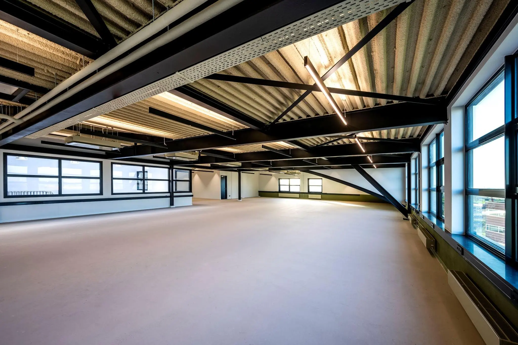 Licht en ruim industrieel kantoorinterieur aan de Singaporestraat met grote ramen en zichtbare plafondconstructie.