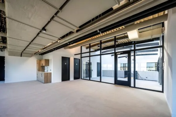 Moderne, industriële kantoorruimte aan de Singaporestraat met glazen wand, kitchenette en zicht op een binnenplaats.
