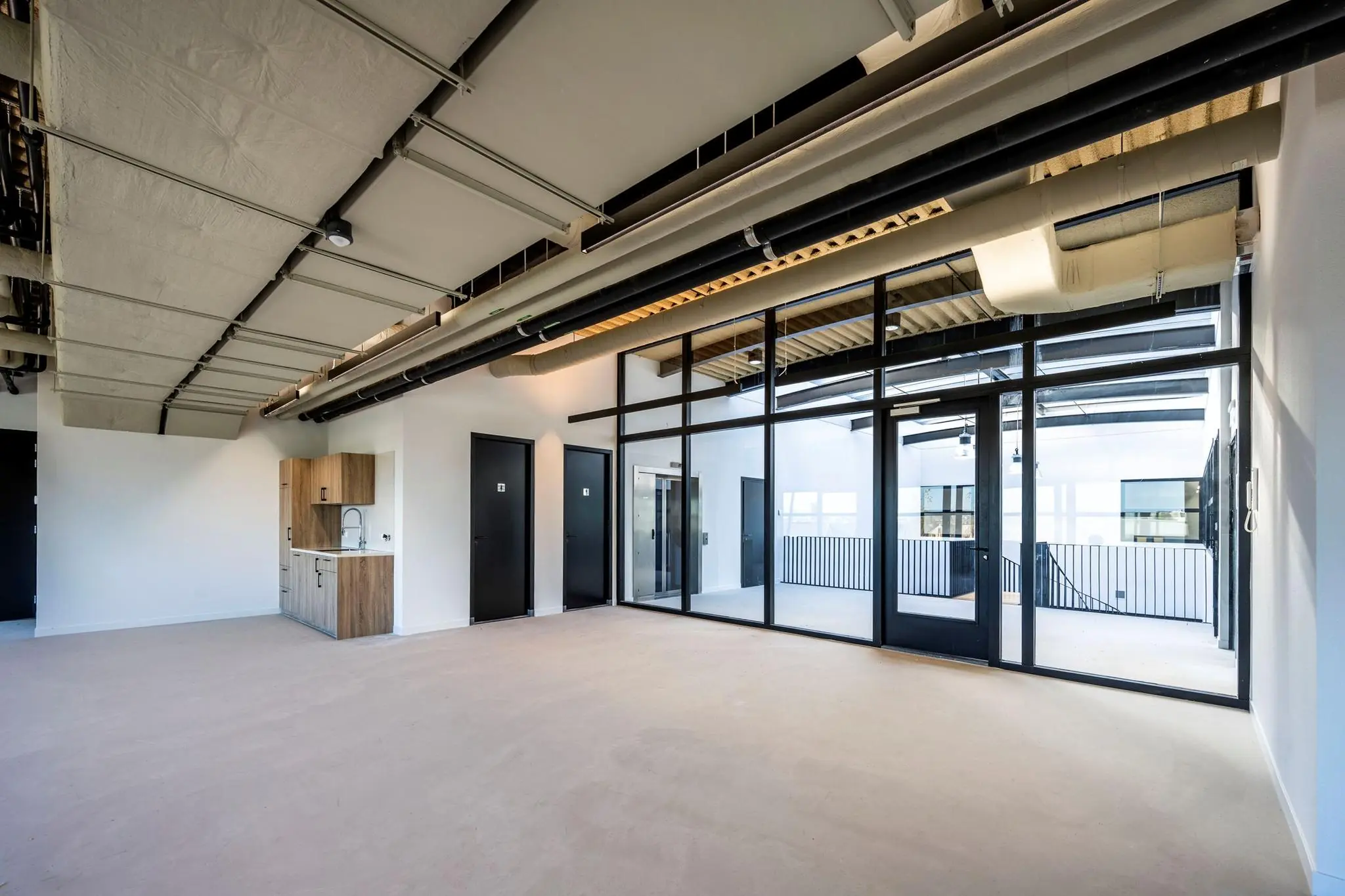 Moderne, industriële kantoorruimte aan de Singaporestraat met glazen wand, kitchenette en zicht op een binnenplaats.