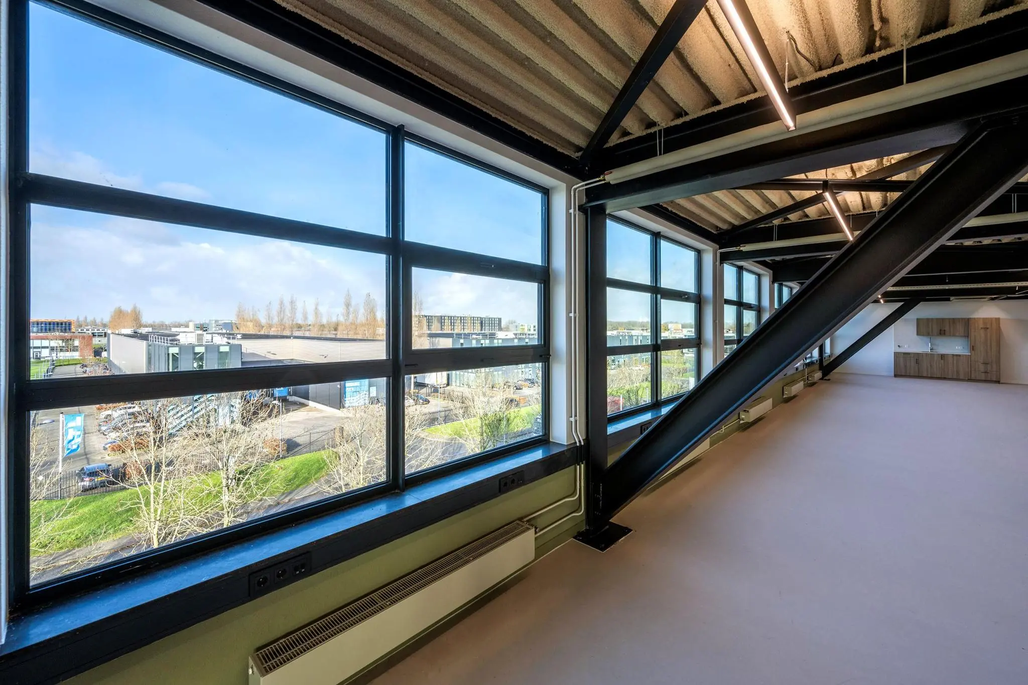 Modern industrieel kantoorinterieur met grote ramen en uitzicht op bedrijven aan de Singaporestraat.