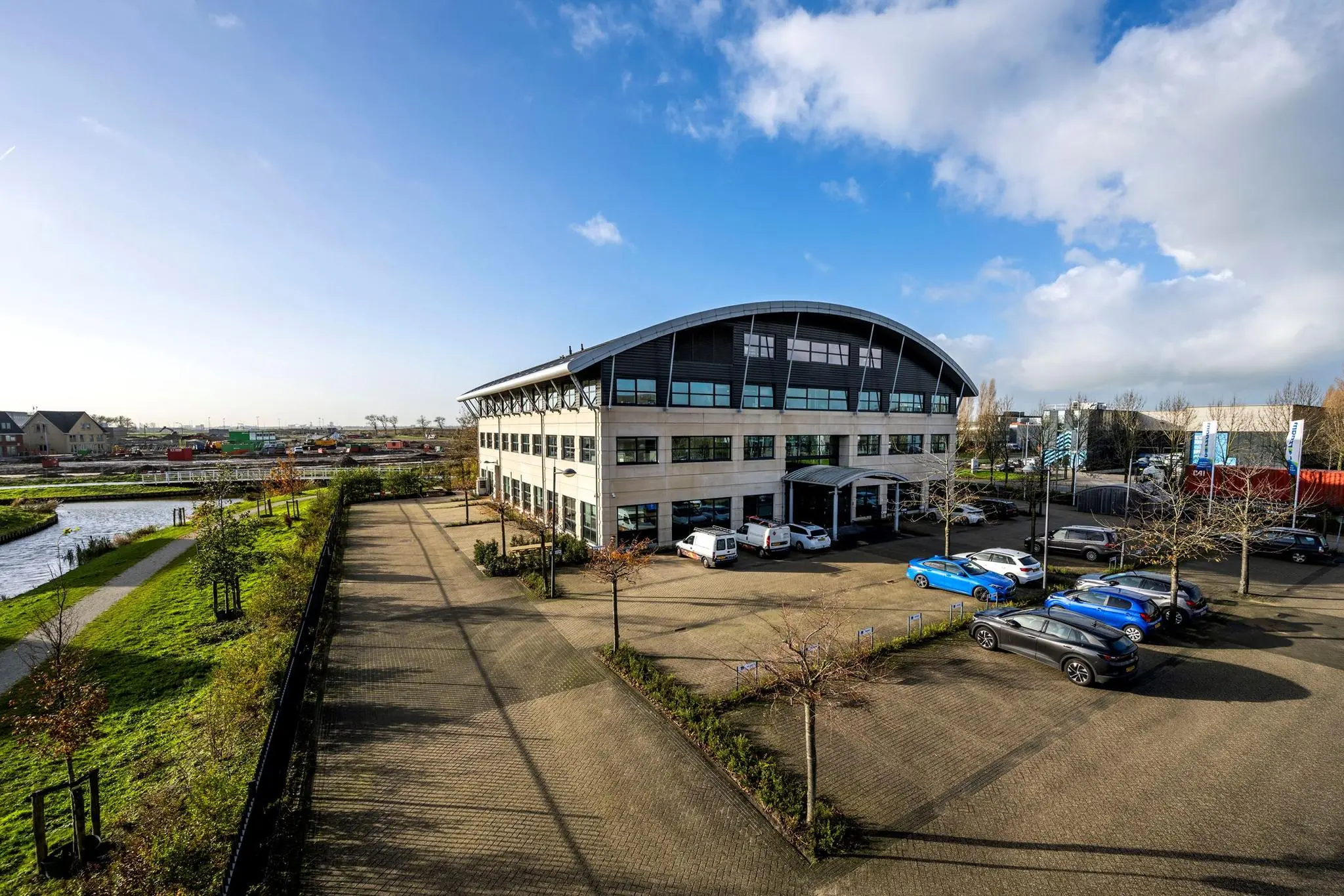 Modern kantoorgebouw aan de Singaporestraat met omliggende parkeerplaatsen en waterpartij op de voorgrond.