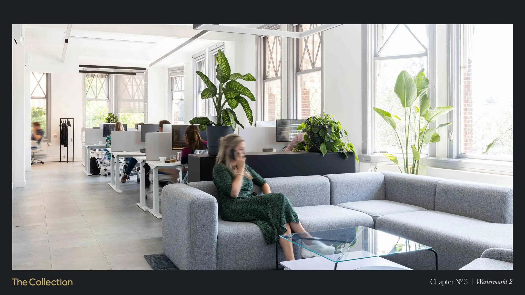 Moderne en lichte kantoorruimte aan de Westermarkt met werkplekken, veel planten en een zithoek met een vrouw die telefoneert.