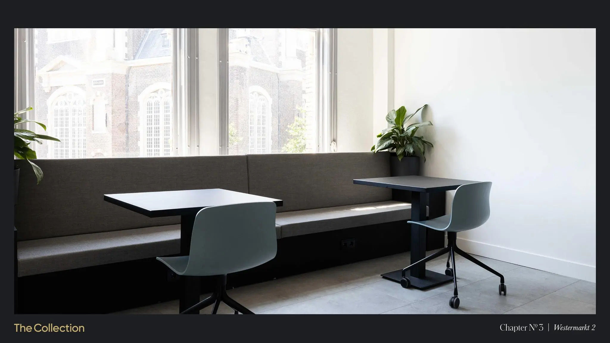 Moderne werkruimte met twee bureaus, stoelen en een bank bij grote ramen met uitzicht op de Westermarkt in Amsterdam.