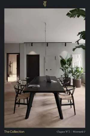 Stijlvol ingericht kantoor aan de Westermarkt met een zwarte houten tafel, designstoelen, een laptop en grote kamerplanten.