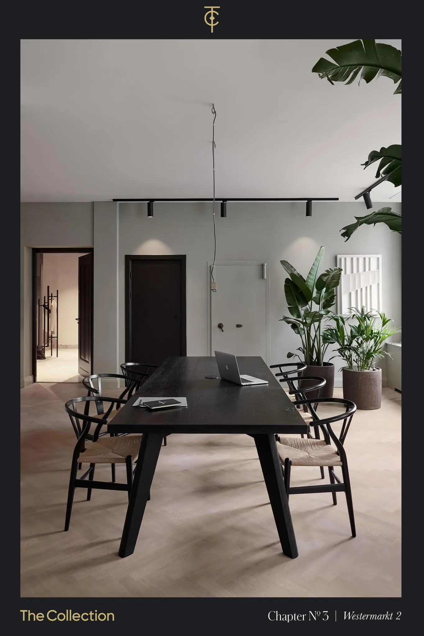 Stijlvol ingericht kantoor aan de Westermarkt met een zwarte houten tafel, designstoelen, een laptop en grote kamerplanten.