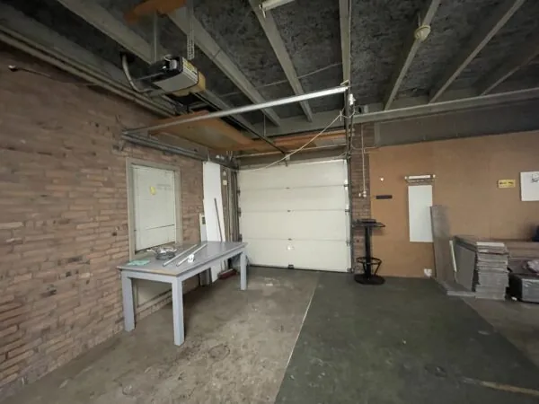 Garage aan de Ophelialaan met een werktafel, stapel tegels en een gesloten garagedeur.
