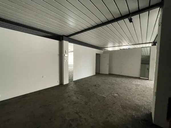 Lege, donkergrijze ruimte met systeemplafond en open deur aan de Ophelialaan.