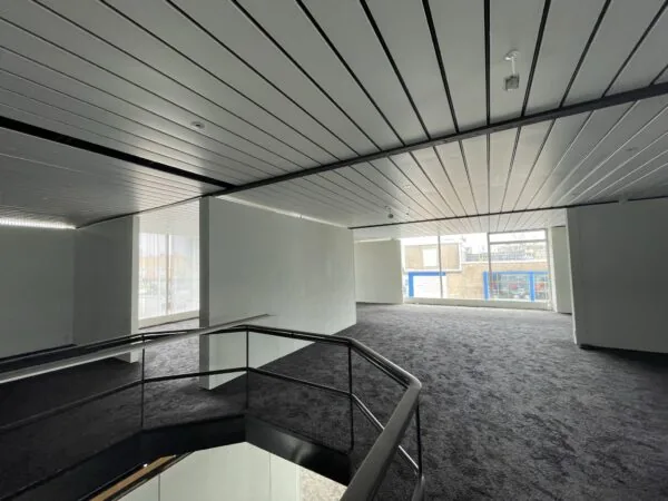 Lichte, leegstaande kantoorruimte aan de Ophelialaan met tapijtvloer en grote ramen.