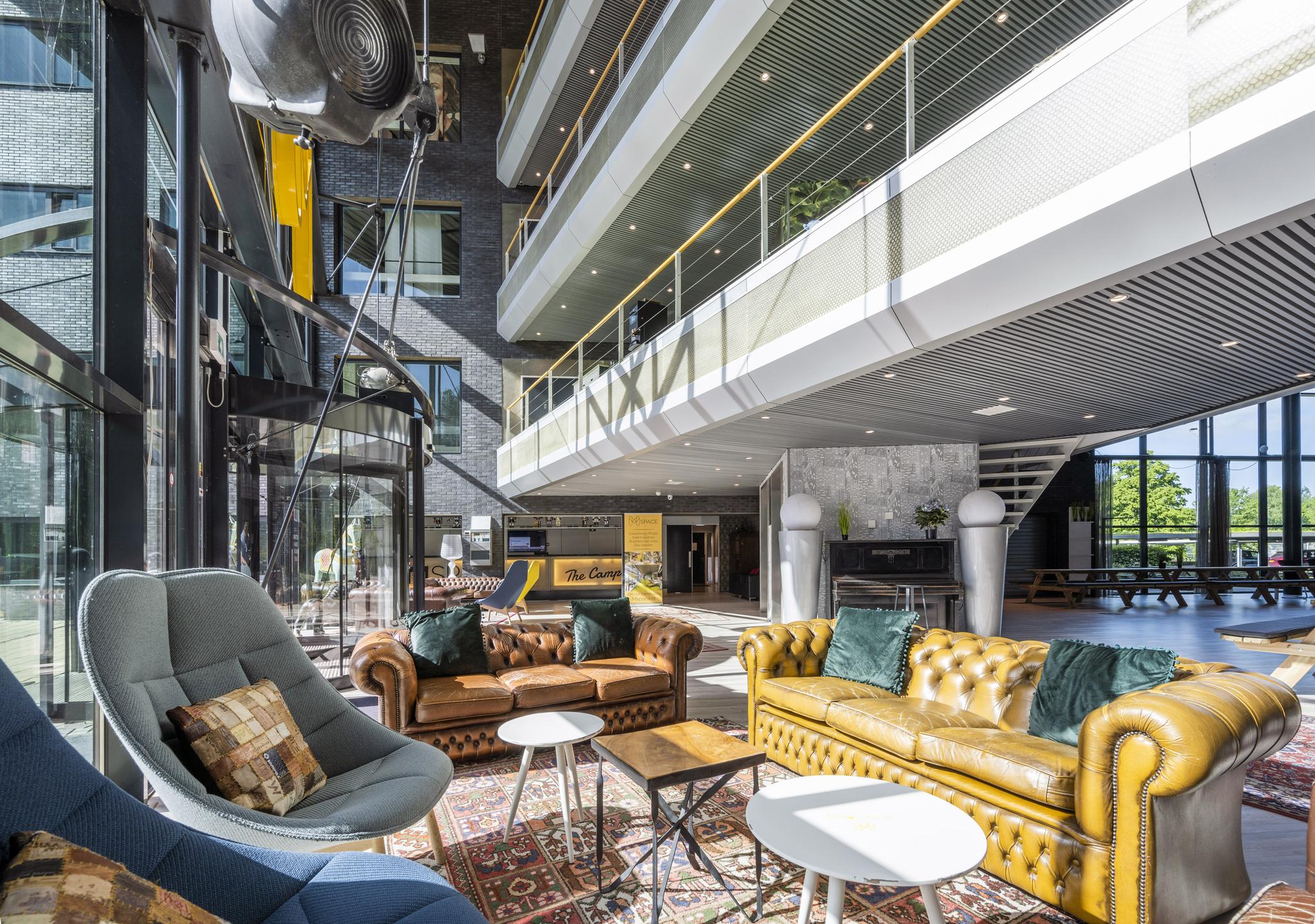 Moderne en zonnige lobby aan de Prof. W.H. Keesomlaan met vintage leren banken en hoge glazen ramen.