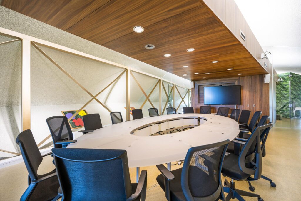 Moderne vergaderruimte aan de Prof. W.H. Keesomlaan met een ovaal wit conferentietafel, zwarte bureaustoelen en een groot scherm aan de muur.
