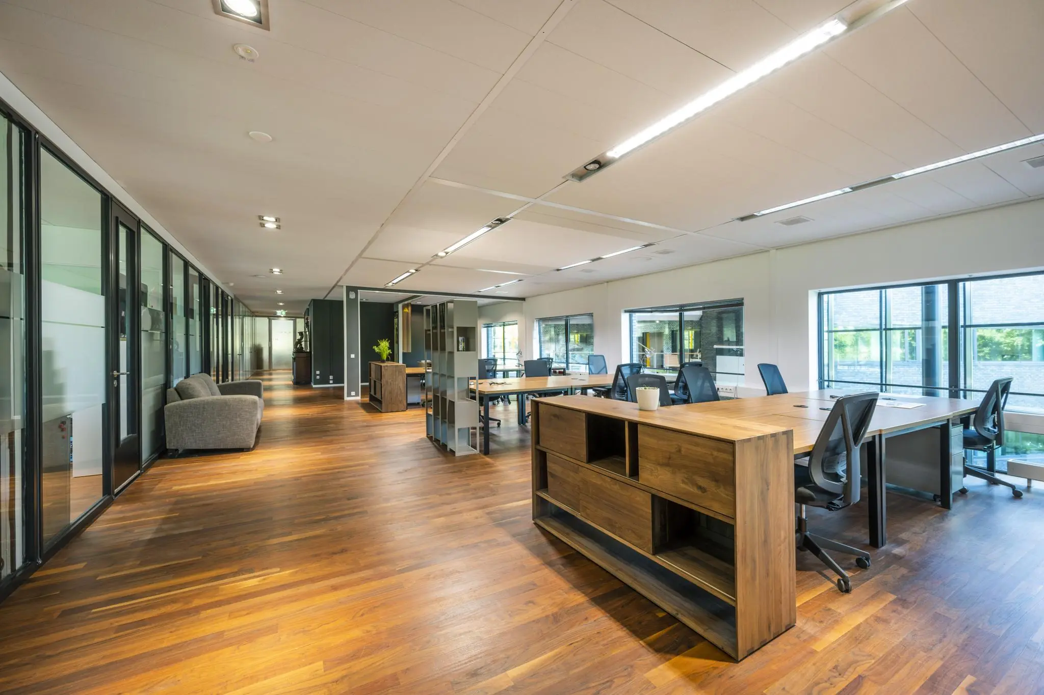 Modern en licht kantoorinterieur aan de Prof. W.H. Keesomlaan met houten vloer, glazen wanden en flexwerkplekken.