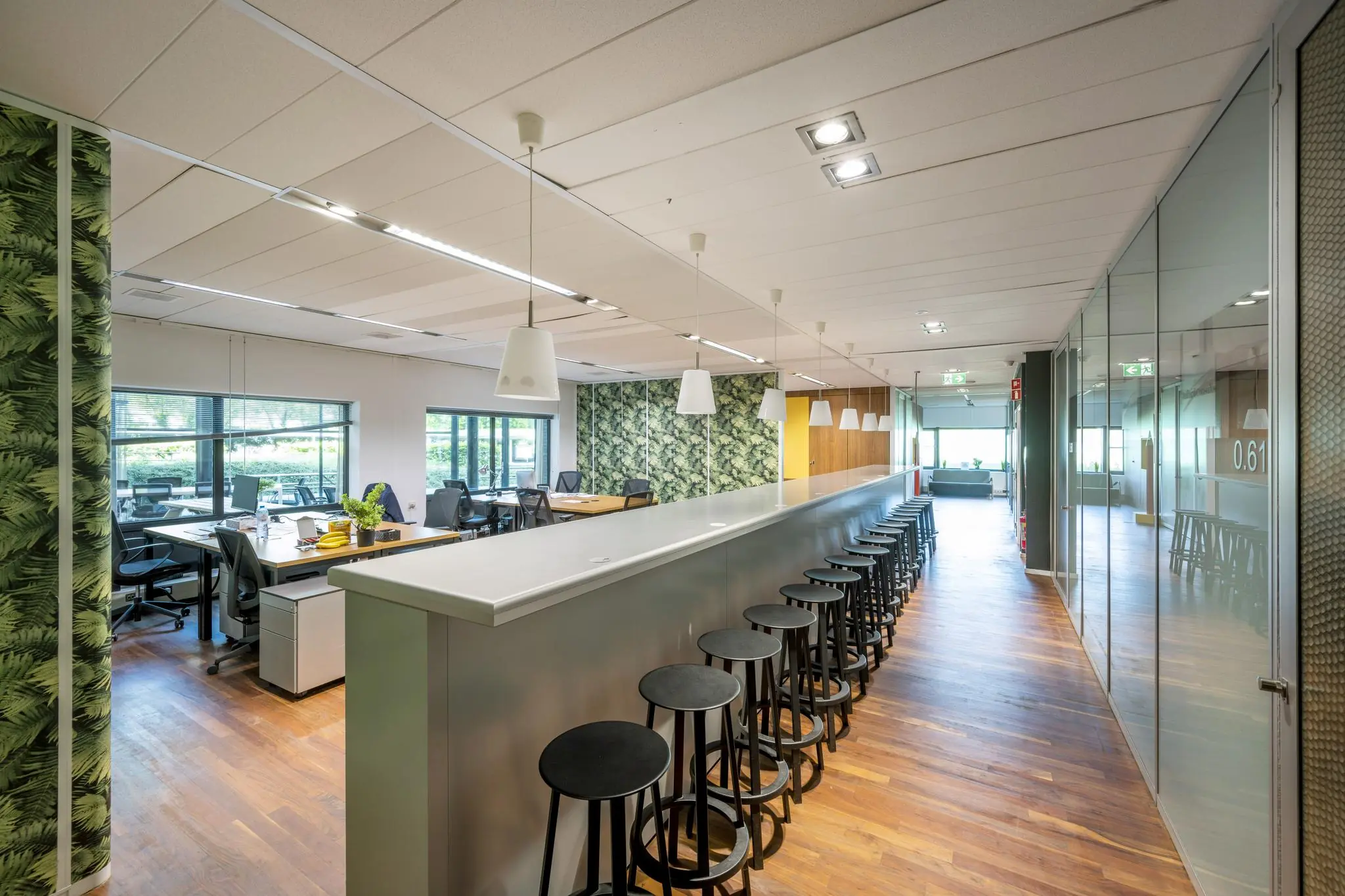 Moderne kantoorruimte aan de Prof. W.H. Keesomlaan met een lange bar, barkrukken, open werkplekken en groene accenten.