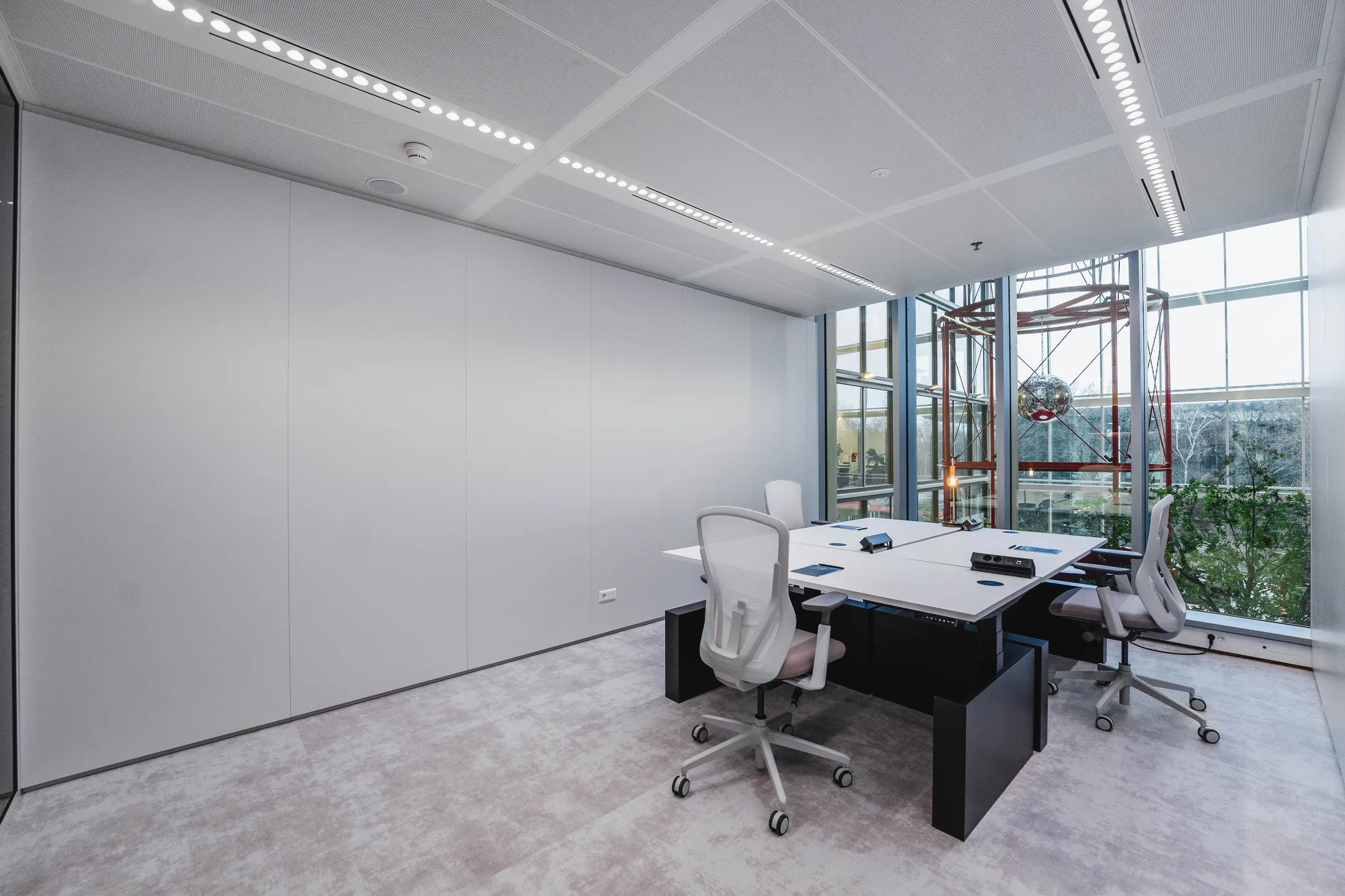 Moderne vergaderruimte met vier bureaustoelen en glazen ramen met uitzicht op buiten.