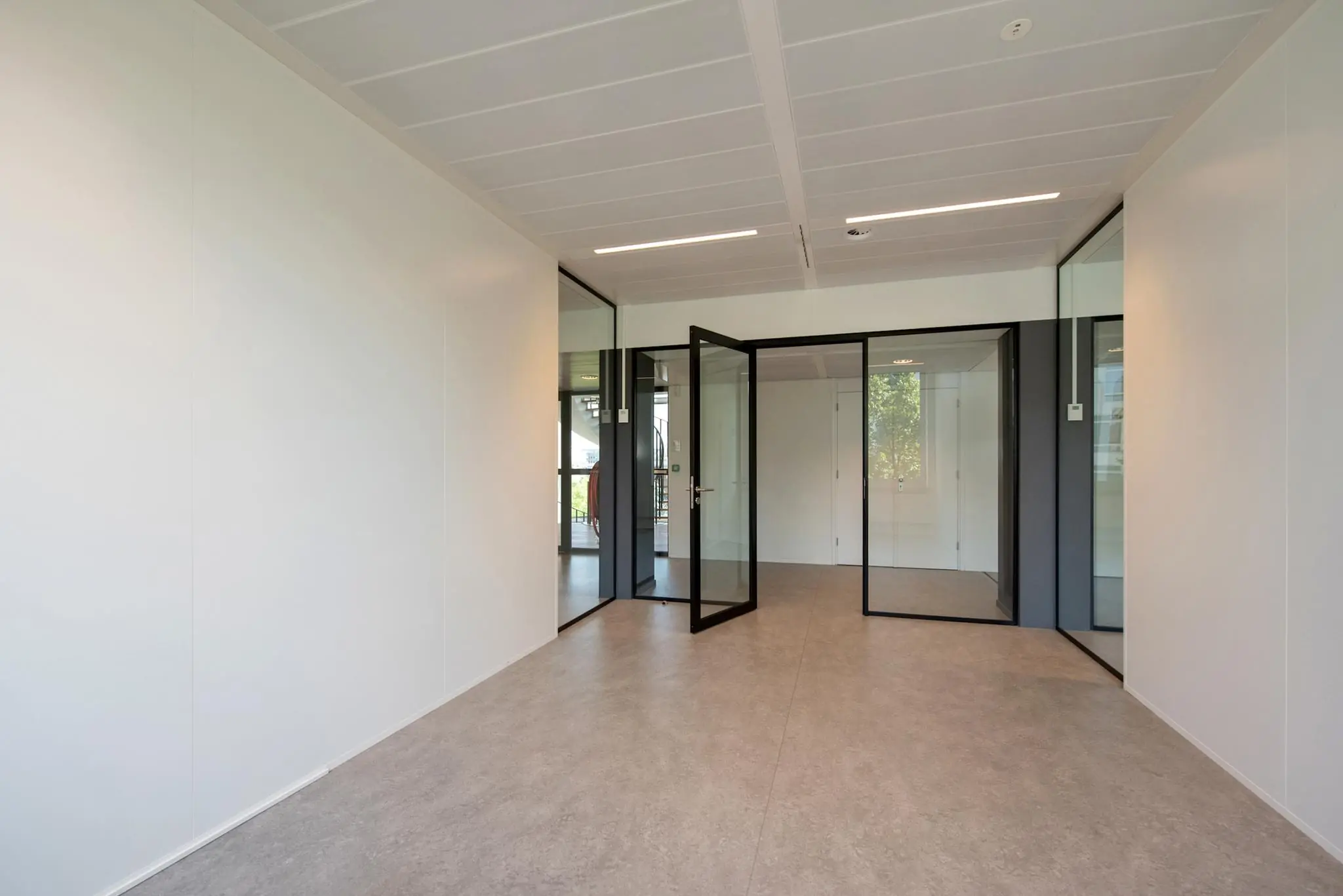 Leeg en modern kantoorinterieur aan de Bezuidenhoutseweg met glazen wanden en openstaande deur.