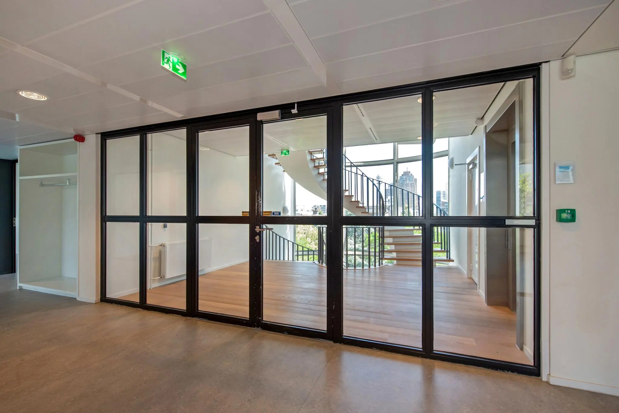 Moderne kantoorruimte aan de Bezuidenhoutseweg met glazen wand en trap met uitzicht op de stad.