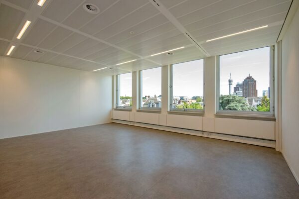 Lege, moderne kantoorruimte aan de Bezuidenhoutseweg met grote ramen en uitzicht op de skyline van Den Haag.