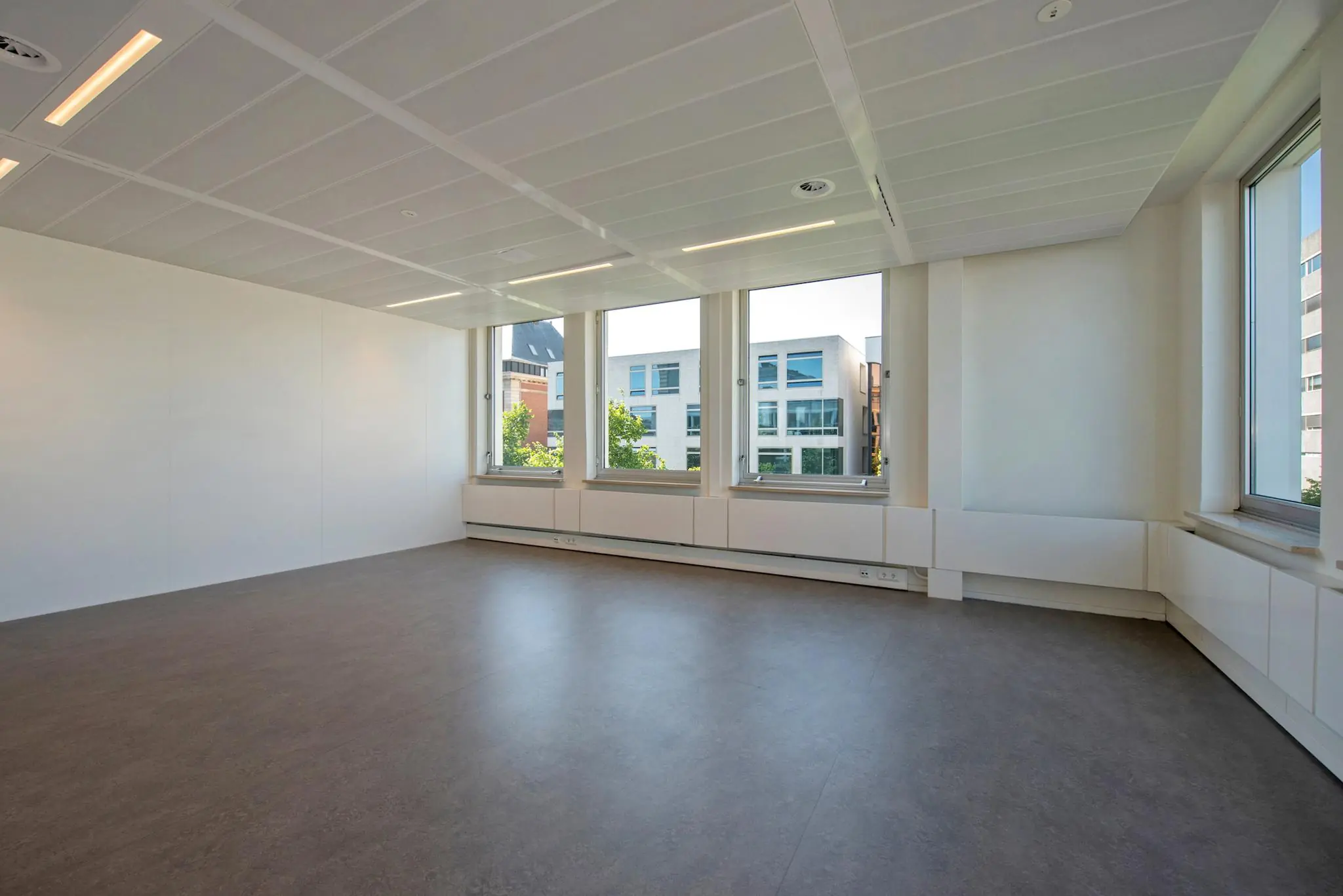 Licht en modern leeg kantoor met grote ramen aan de Bezuidenhoutseweg.