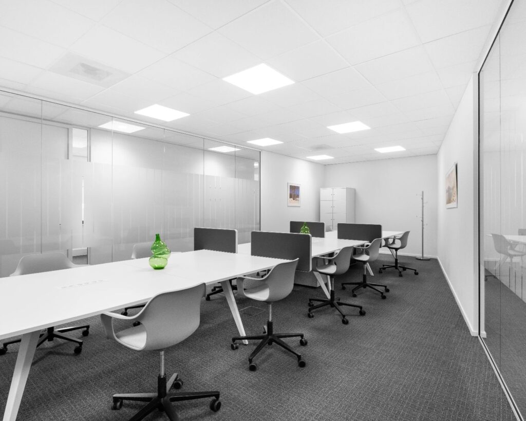 Moderne, minimalistische kantoorruimte met witte bureaus, grijze stoelen en groene decoratieve vazen.
