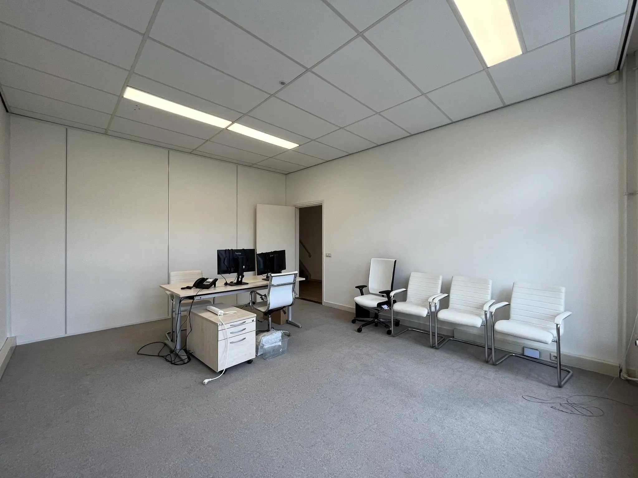 Kantoorruimte aan de Ramstraat met twee werkplekken, vier witte stoelen en een neutraal interieur.