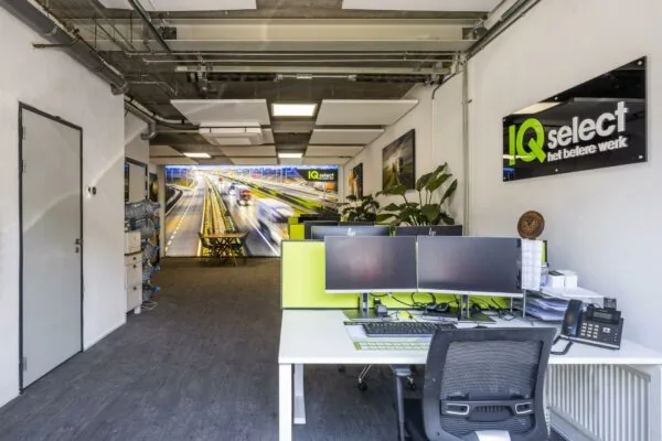 Modern kantoorinterieur van IQ Select aan de Asterweg met werkplekken, computers en een wandfoto van een snelweg.