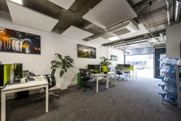 Modern kantoorinterieur aan de Asterweg met werkplekken, grote waterflessen en industriële afwerking.