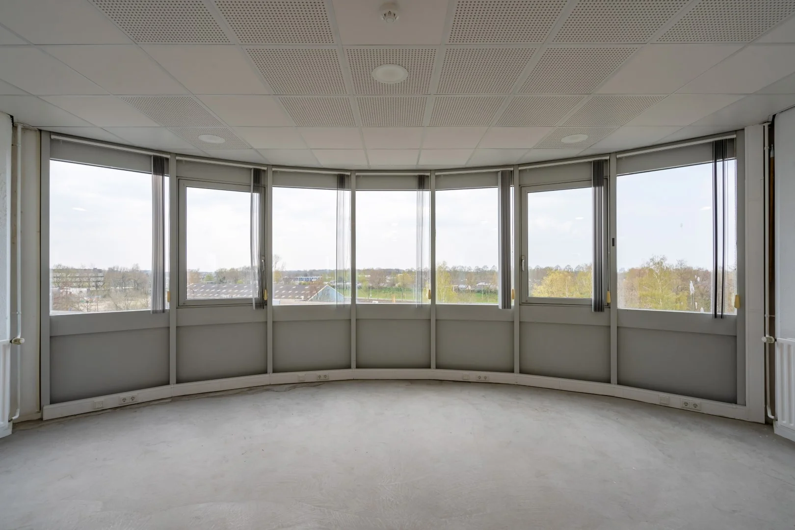Leeg, licht kantoor met gebogen muur en grote ramen aan de Printerweg.