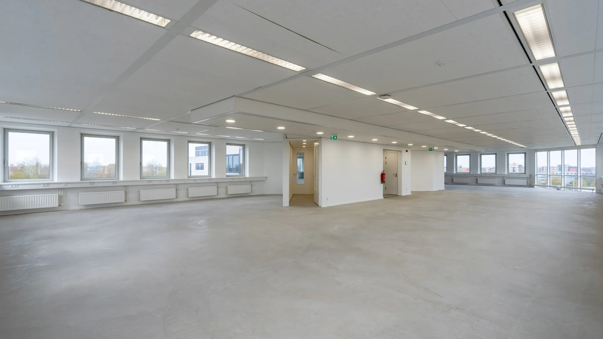 Leeg en licht kantoorpand aan de Printerweg met grote ramen en systeemplafond.