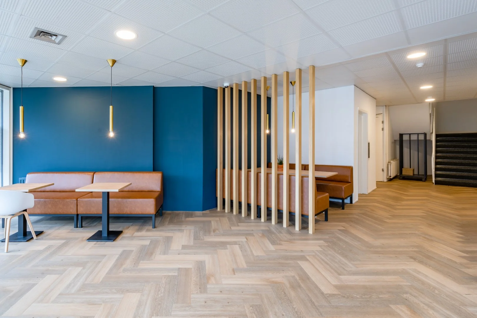 Moderne wachtruimte met leren bankjes, houten vloer en een blauwe accentmuur aan de Printerweg.